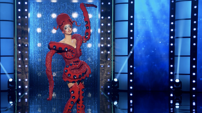 a drag queen walks the runway dressed as a red octopus